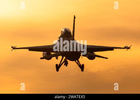 A F-16 fighter jet is ready to land at an airbase during a beautiful sunset. Stock Photo