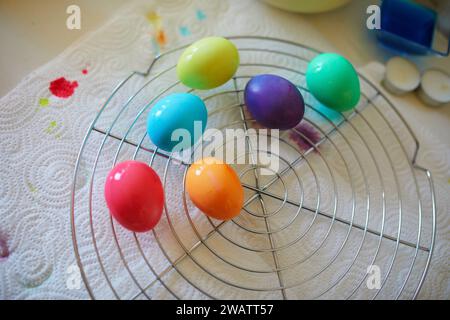 Using food coloring to dye Easter eggs at home. Painting colorful eggs for Easter hunt. Getting ready for Easter celebration. Family traditions. Stock Photo