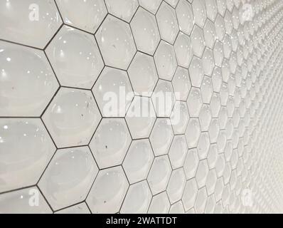 A wall tiled in white hexagons Stock Photo