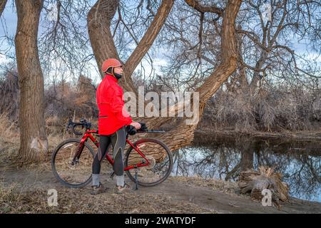 senior male cyclist with a gravel bike on a shore of the Poudre River in northern Colorado in winter scenery Stock Photo