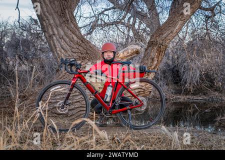 senior male cyclist with a gravel bike on a shore of the Poudre River in northern Colorado in winter scenery Stock Photo