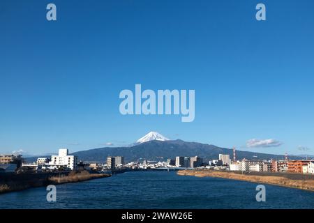 The snow-covered peak of Mount Fuji seen on a sunny day from the Kano River in Numazu City in Shizuoka Prefecture, Japan Stock Photo