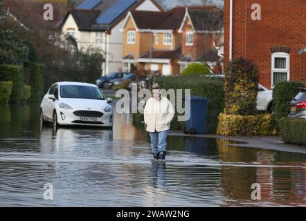 Brampton, UK. 06th Jan, 2024. A resident tests the depth of the flood water covering Centenary Way as the River Great Ouse bursts its banks at Brampton. Flood alerts remain in place as waters continue to rise in the east of England following storm Henk. Main rivers the River Great Ouse and the River Nene have burst their banks and spilled onto the surrounding countryside and with drains full to capacity they are backing up in residential areas. Credit: SOPA Images Limited/Alamy Live News Stock Photo