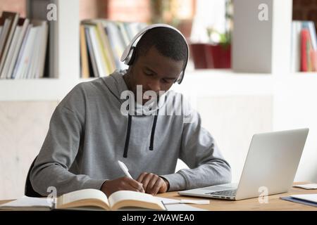 Focused biracial guy writing studying using laptop Stock Photo