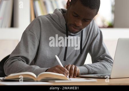Focused african American guy make notes studying on laptop Stock Photo