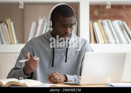 Frustrated biracial guy make notes taking online course Stock Photo