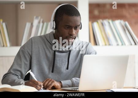 Focused biracial guy make notes watching educational webinar Stock Photo