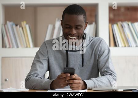 Smiling biracial male student have fun using smartphone Stock Photo