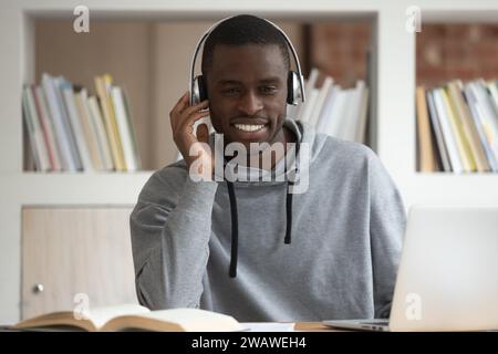 Smiling biracial guy in headphones watch online course on laptop Stock Photo