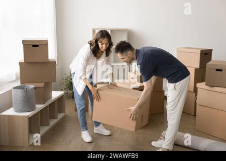 Happy busy couple of home owners unpacking cardboard boxes Stock Photo