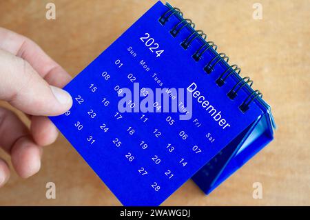 Hand showing December 2024 table calendar on wooden background. Calendar concept. Stock Photo