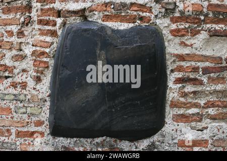 An old, abandoned, medieval wall made of bricks and a large stone. Stock Photo