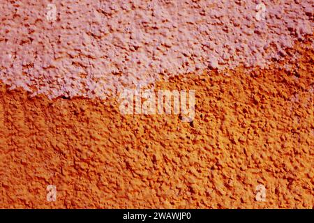 Old plaster painted in two different colors. Orange and pink color of the wall surface. Stock Photo