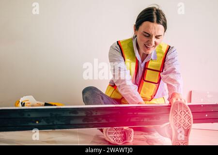 Women worker builder foreman accident steel frame fall on leg ankle serious injury painful need medical emergency help at construction site Stock Photo