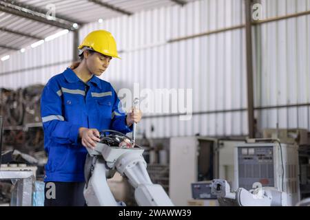 Engineer women mechanic technician working fix repair service replacing broken part old robotic arm machine in workshop. Stock Photo