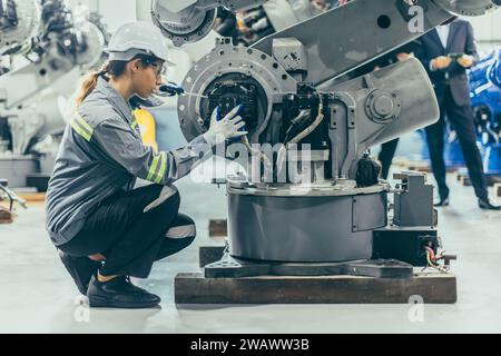 Engineer robotic mechanic women technician working in advance robotic industry plant work assembly robot arm repair fix maintenance or service large m Stock Photo