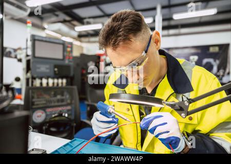Electrician technician caucasian male using hot soldering iron to electrical bond electricity wire fix repair power line cable with solder tin and lea Stock Photo