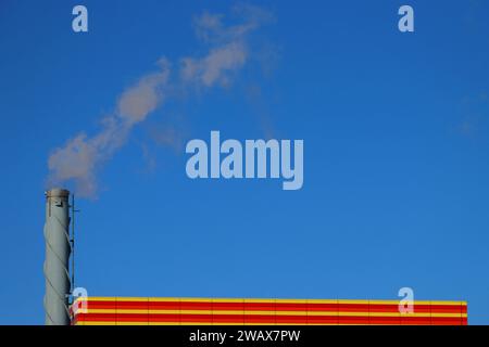 chimney with smoke coming out in a factory. Concept of heating in winter, environmental pollution. Stock Photo