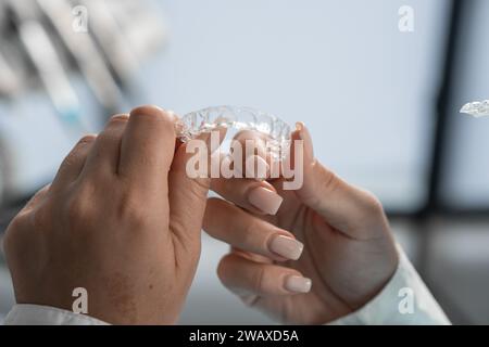 The dentist carefully holds the mouth guard in his hands, preparing for the procedure and demonstrating his adaptability to the highest standards of Stock Photo