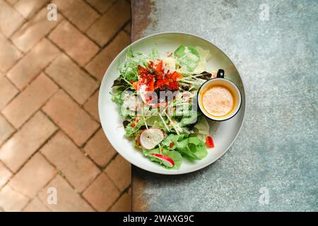Fresh Green vegan salad from green leaves mix and vegetables. Top view on gray stone table. Greek salad of fresh cucumber, tomato, sweet pepper, lettu Stock Photo