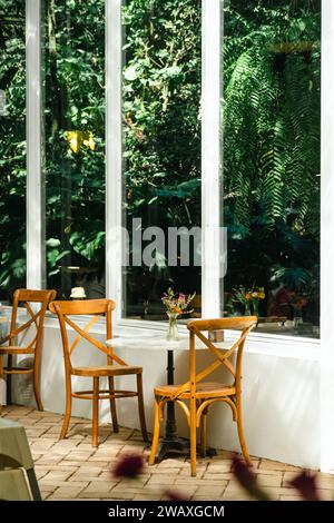 wooden terrace with garden furniture surrounded by greenery, wood sofa and table made of metal and wood in the yard. Interior design of summer with st Stock Photo