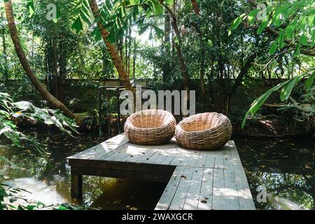 wooden terrace with garden furniture surrounded by greenery, wood sofa and table made of metal and wood in the yard. Interior design of summer with st Stock Photo