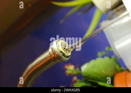 A close up photo of a silver metal sink kitchen tap dripping water into the sink. Stock Photo