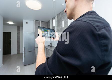 Worker with tablet computer checking alarm system indoors Stock Photo