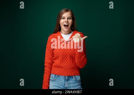 Joyful lucky woman wearing a red sweater on a dark green background Stock Photo