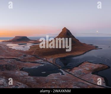 Beautiful aerial view of the Kirkjufell high mountain in Iceland, on the Snaefellsnes peninsula. Sunset Sunrise soft orange light. West Iceland. Stock Photo