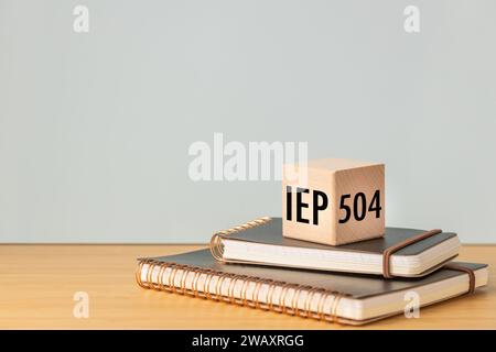 IEP Individual Education Plan Symbol. Business concept, IEP 504 program,  text on a natural wooden block placed on school notebooks, copy space, Stock Photo