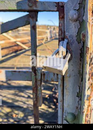 A locked rusty gate secured with a padlock is intended to prevent unauthorised persons from entering. Stock Photo