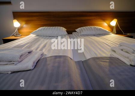 minimal double bed with white mattress in economy hotel bedroom. Stock Photo