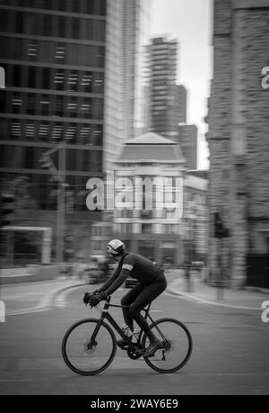 A cyclist on a road bike speeds along the road near Liverpool Street in London England UK Stock Photo