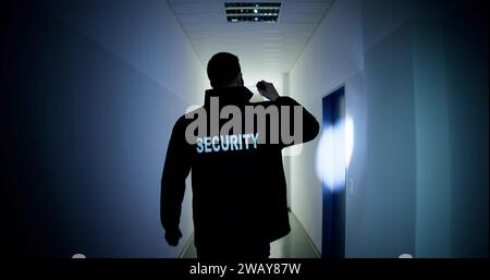 Male Security Guard Holding Flashlight Standing In Corridor Of The Building Stock Photo
