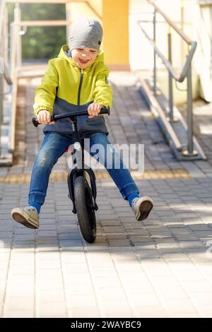 Little boy on a bicycle. Caught in motion, on a driveway. Preschool child's first day on the bike. The joy of movement. Little athlete learns to keep Stock Photo