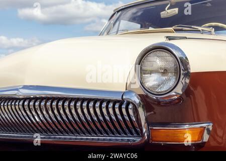 Headlight of an old car, close-up of a round headlight. Classic car show, close-up on vehicle headlights, vintage color. Stock Photo