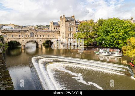 BATH, UK - 12TH AUGUST 2023: Pulteney Bridge over the River Avon in Bath England during the day. A boat and people can be seen. Stock Photo