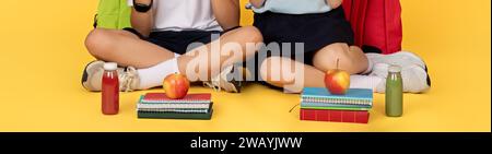 Schoolchildren sitting cross-legged with healthy snacks and notebooks Stock Photo