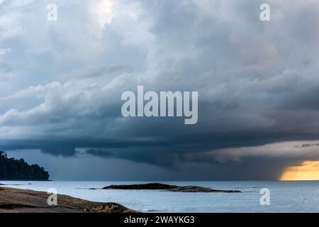 Huge offshore thunder storm and rain at sunset over a tropical ocean Stock Photo
