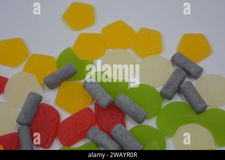 Mix, assorted of unusual branded factory gummy candies in the form of gray, metal cylinders, colored elements, capsules, talismans located on a white. Stock Photo