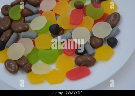 Mix, assorted of unusual branded factory gummy candies in the form of metal cylinders, colored elements, capsules, talismans and chocolate stones. Stock Photo