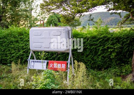 water tank for fire fighting sitting in a field near a home in central hokkaido japan Stock Photo