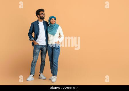 Stylish arab muslim couple in trendy clothes standing confidently and looking away Stock Photo