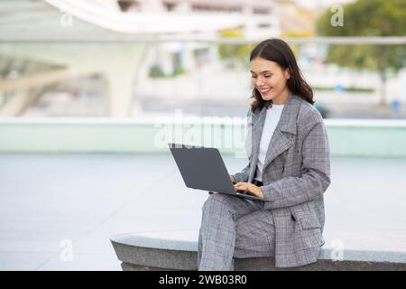 Successful young manager woman programming on laptop outside Stock Photo