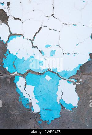 Abstract vertical background of shabby concrete wall surface with bright turquoise and white paint and weathered parts. Stock Photo