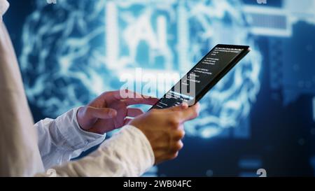 IT developer writing artificial intelligence script code in startup workspace on tablet terminal. Experienced programmer doing maintenance work in high tech facility updating AI systems Stock Photo