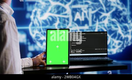 Certified admin using green screen tablet to write artificial intelligence script code in startup workspace. Qualified expert doing maintenance work in high tech establishment updating AI systems Stock Photo