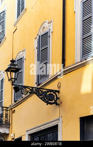 Picturesque street lamp with a wall painted with the traditional 'giallo parma' color, in Parma city center, Emilia Romagna region, Italy Stock Photo