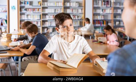 Boy gives the read books to the librarian in school library Stock Photo